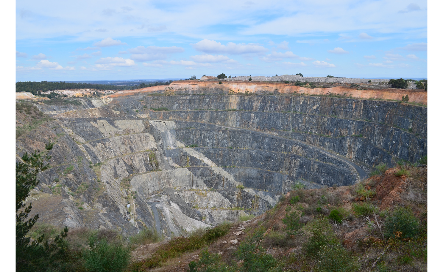 Cornwall Pit, Greenbushes Mine, WA. The pegmatite intrusions show as lighter bands. Source: Mindat.org